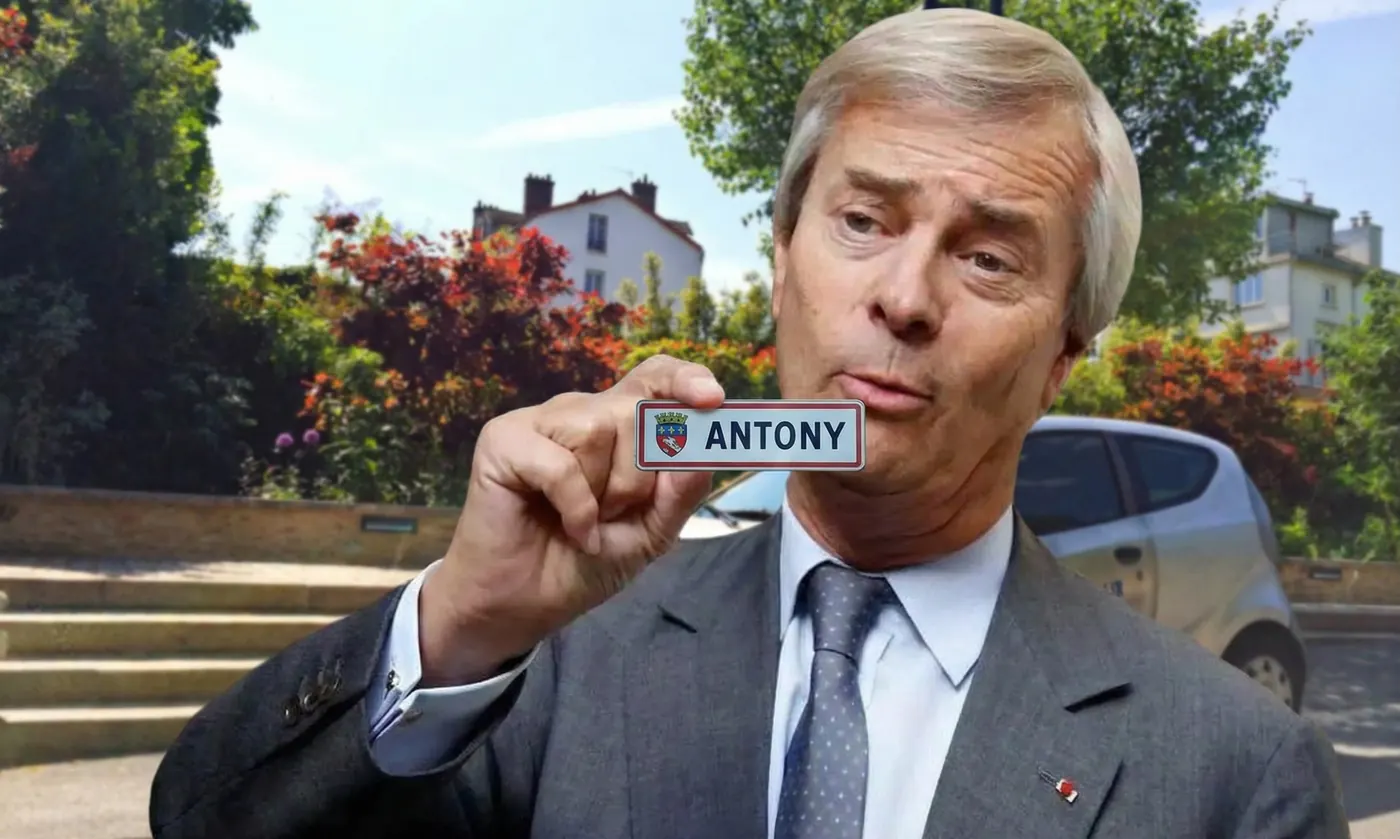 Photomontage : un homme en costume gris, l'air moqueur, brandit une petite plaque « ANTONY » devant une rue arborée où stationne une petite voiture électrique grise.