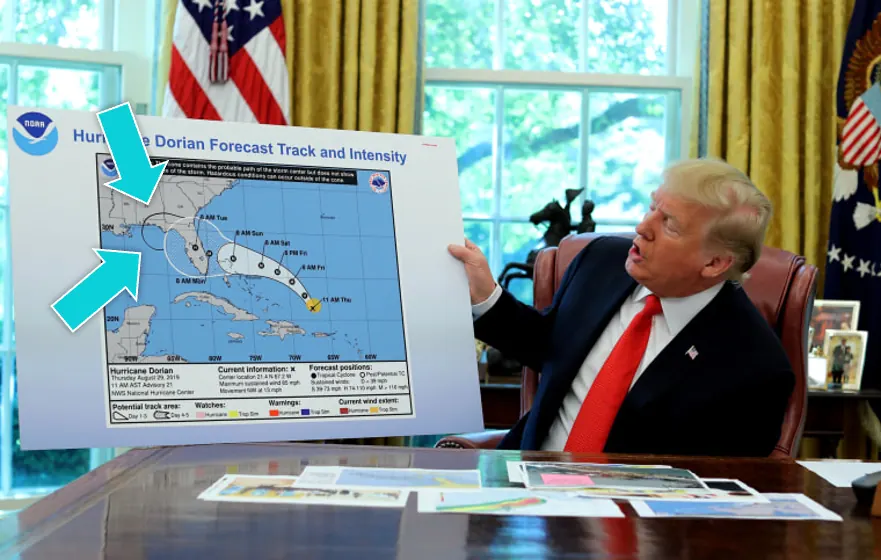 Un homme en costume, dans un bureau officiel, brandit une carte de prévision de l'ouragan Dorian ; deux flèches montrent un tracé noir ajouté qui prolonge la zone d'impact.