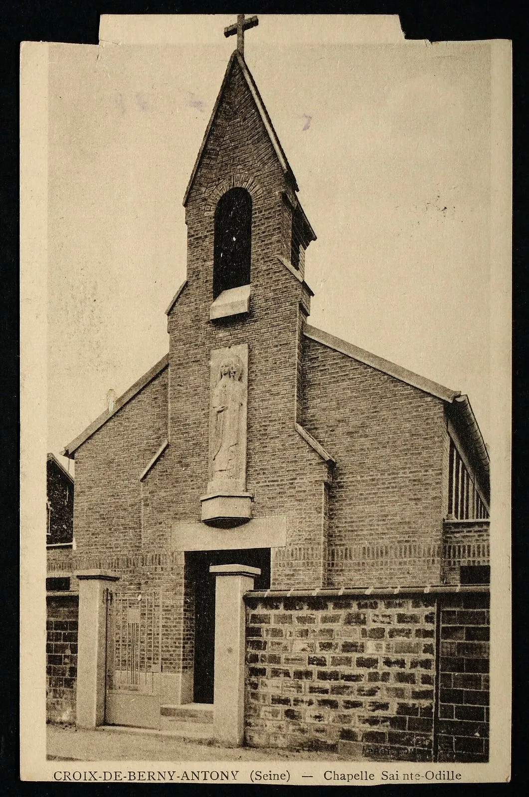 Carte postale ancienne « Croix-de-Berny-Antony (Seine), chapelle Sainte-Odille » : la même façade de briques avec son clocheton et sa statue, alors fermée par un muret et un portail.