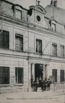 Carte postale ancienne d'Antony montrant la façade de l'ancienne mairie, avec ses colonnes à l'entrée et un groupe d'hommes devant la porte, un jour d'élections.