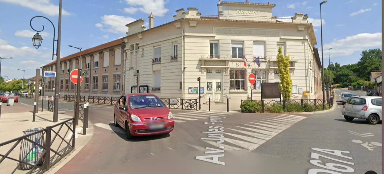 Vue actuelle du groupe scolaire Jules Ferry à Antony : grand bâtiment d'angle crème au fronton marqué « Antony », au carrefour de l'avenue Jules Ferry.